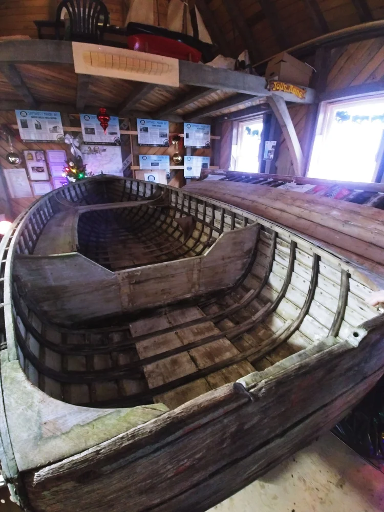 Interior view of the Ackroyd skiff showing weathered ribs, planking, and thwart inside the boat shed