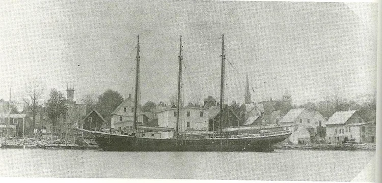 Historic photograph of a three-masted schooner alongside the Mahone Bay shipyards