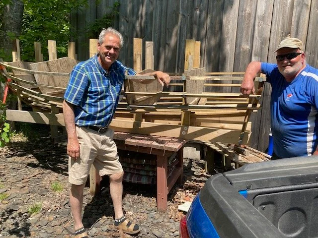 David Sampson and Chris Herrnberger standing beside the completed Herreshoff dinghy tender
