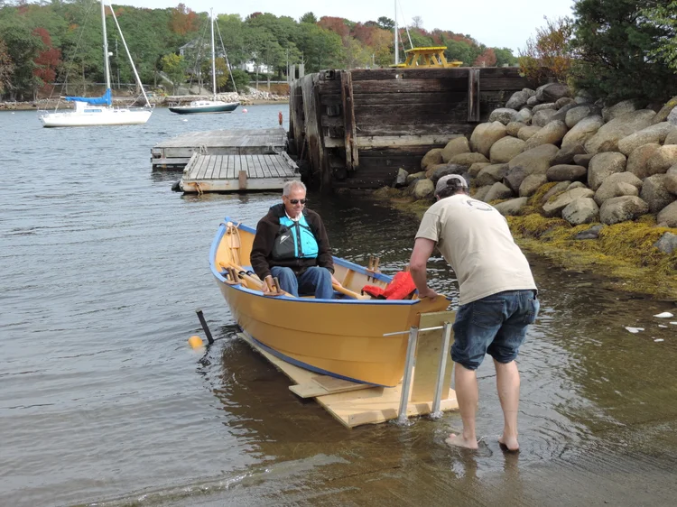 A Co-op member rowing the restored LaHave Dory off the launch ramp on a calm autumn day