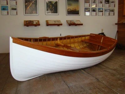 The fully restored Lawley tender on display before MICA's fundraising auction — white hull, varnished interior and trim