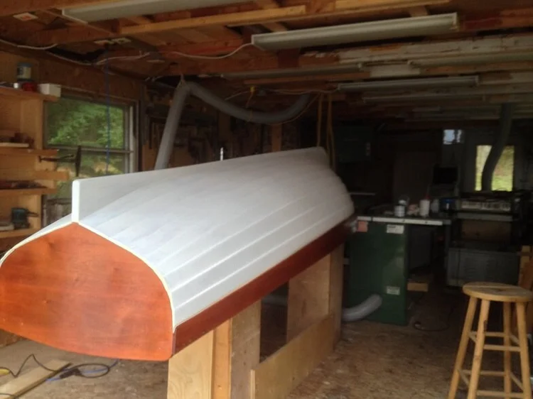The Lawley tender upturned on horses with freshly painted white hull and varnished mahogany transom