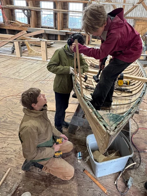 Three students working on the Pintail Skiff at Andrew Rhodenizer's Big Boat Shed, repairing the stem and frames
