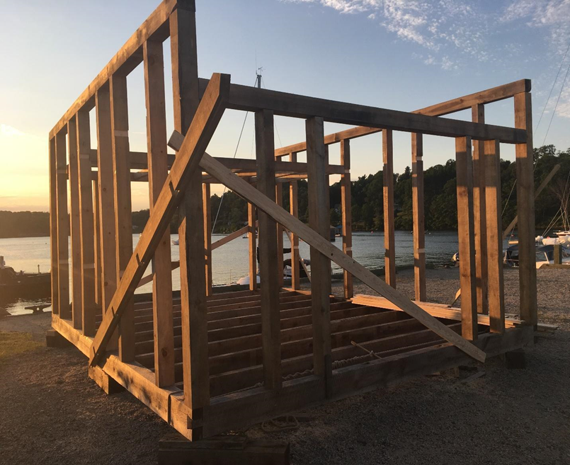 Wall and rafter framing of the boatbuilding shed standing against an evening sky on the waterfront