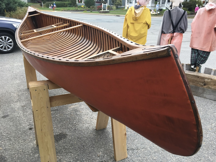The fully restored Tremblay canoe on a wooden cradle in the street, ready for the MICA fundraising auction